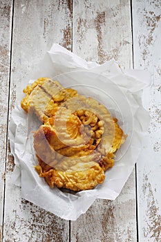 Fried coalfish on waxed paper, wooedn background