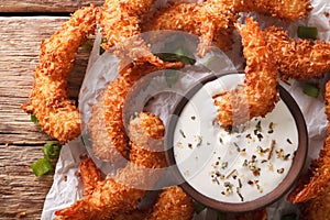 Fried coconut shrimp close-up and a cream sauce on the parchment