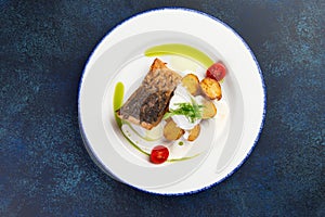 Fried cod fillet and new potatoes in a plate