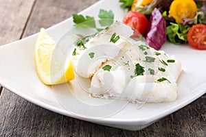 Fried cod fillet and salad in plate