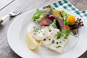 Fried cod fillet and salad in plate