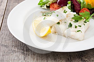 Fried cod fillet and salad in plate