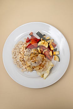 fried cod fish with onion, vegetables, rice and olive oil on plate