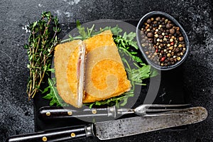 Fried cordon bleu meat chicken cutlet with ham and cheese. Black background. Top view