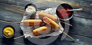 Fried corn dogs served on tissue near sauces photo