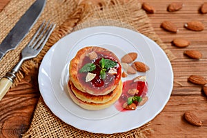 Fried cottage cheese pancakes with berry jam, almonds and mint on a white plate. Syrniki recipe. Low carb cottage cheese pancakes