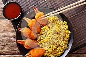 Fried crab claws tempura with rice close-up on a plate. Horizontal top view