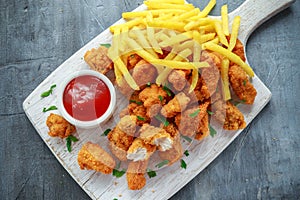 Fried crispy chicken nuggets with french fries and ketchup on white board