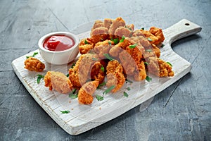 Fried crispy chicken nuggets with ketchup on white board