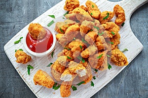 Fried crispy chicken nuggets with ketchup on white board