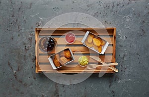 Fried crispy chicken nuggets and legs with ketchup and cola on wooden tray. Street food concept, top view, copy space.