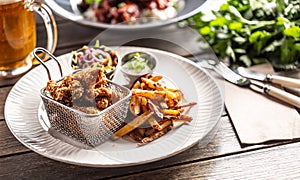 Fried crispy chicken wings with chips, dip and salad served on a table