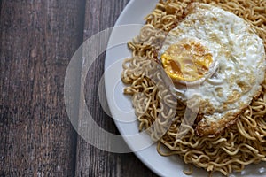 Fried curly noodle with fried egg on top of wooden table ready to be served