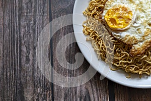 Fried curly noodle with fried egg on top of wooden table ready to be served