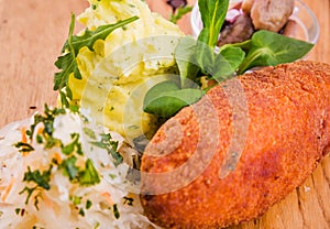 Fried cutlet, mashed potatoes, sauerkraut and pickled mushrooms on a wooden board