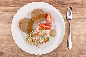 Fried cutlets with vegetable mix, tomatoes and mustard in plate