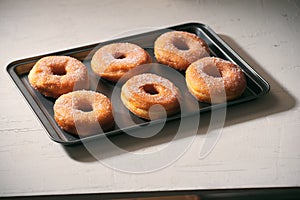 Fried Donuts with Powdered Sugar on metal baking dish