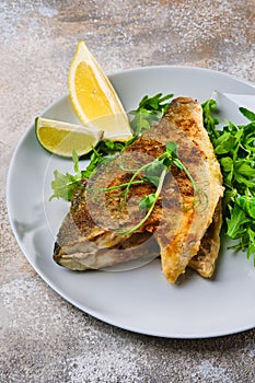 Fried dorada fish with fresh arugula