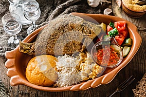 Fried dorado fish with polenta, cheese, scrabble eggs and vegetables on rustic wooden background with Russian vodka drink.