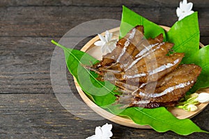 Fried dried fish on mango leaf in wooden dish on wooden table