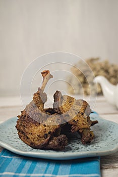 Fried duck on blue plate and napkin against white rustic background