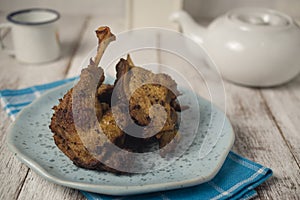 Fried duck on blue plate and napkin against white rustic background
