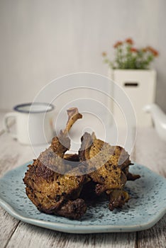 Fried duck on blue plate and napkin against white rustic background