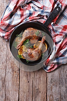 Fried duck legs with oranges, vertical top view, rustic style
