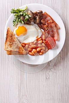 Fried egg with bacon, beans and toast top view vertical