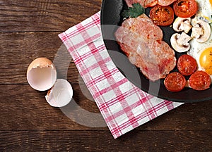 Fried egg bacon champignons tomato parsley in a pan wooden