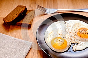 fried egg on black plate on wooden table