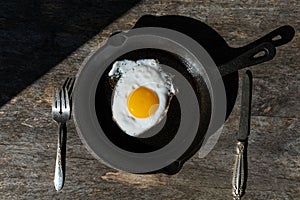 Fried egg in a cast iron pan. Simple breakfast. Hard light.