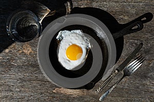 Fried egg in a cast iron pan. Simple breakfast. Hard light.