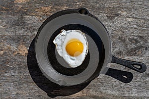 Fried egg in a cast iron pan. Simple breakfast. Hard light.