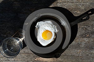 Fried egg in a cast iron pan. Simple breakfast. Hard light.