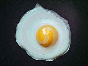 Fried egg. Close up view of the fried egg on a frying pan. Salted and spiced fried egg on cast iron pan