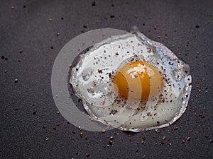 Fried egg. Close up view of the fried egg on a frying pan. Salted and spiced fried egg on cast iron pan