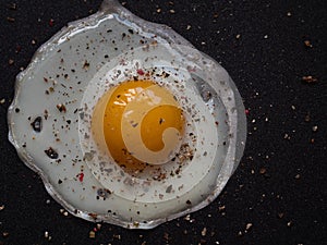 Fried egg. Close up view of the fried egg on a frying pan. Salted and spiced fried egg on cast iron pan