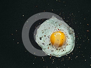 Fried egg. Close up view of the fried egg on a frying pan. Salted and spiced fried egg on cast iron pan