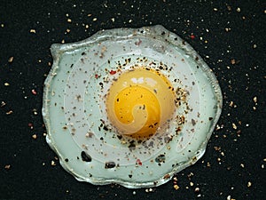 Fried egg. Close up view of the fried egg on a frying pan. Salted and spiced fried egg on cast iron pan