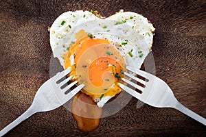 Fried egg with heart shape and two dinner forks, concept love