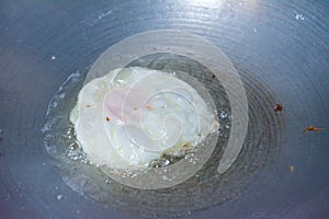 A fried egg with oil on pan.