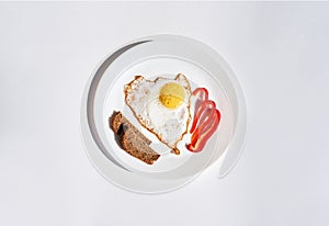 Fried egg, peace pf bread and slices of red pepper on a white plate. Home breakfast