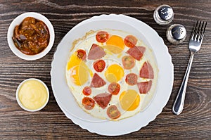 Fried egg with sausage and tomatoes in dish, spices, eggplants