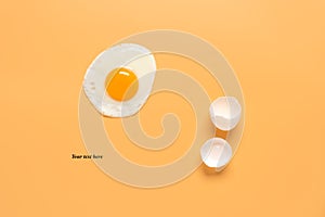 Fried egg and shells on a pastel yellow background. Creative layout. Minimalistic still life. Breakfast concept. Top view, flat