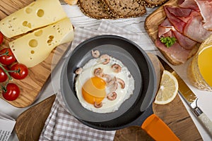 Fried egg with shrimps in pan, cheese, ham, bread and buns