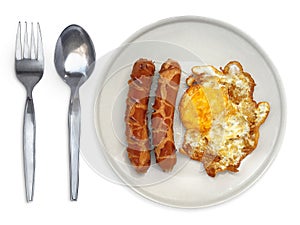 Fried egg side up a plate with spoon and fork on a white background