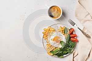 Fried egg, spinach, waffles and cup of coffee espresso on white background