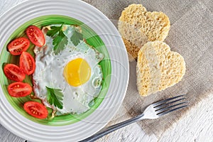 Fried egg, tomatoes, and two heart-shaped toasts. Romantic food