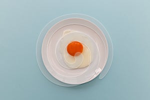 Fried egg and yoke overhead on plate and blue background